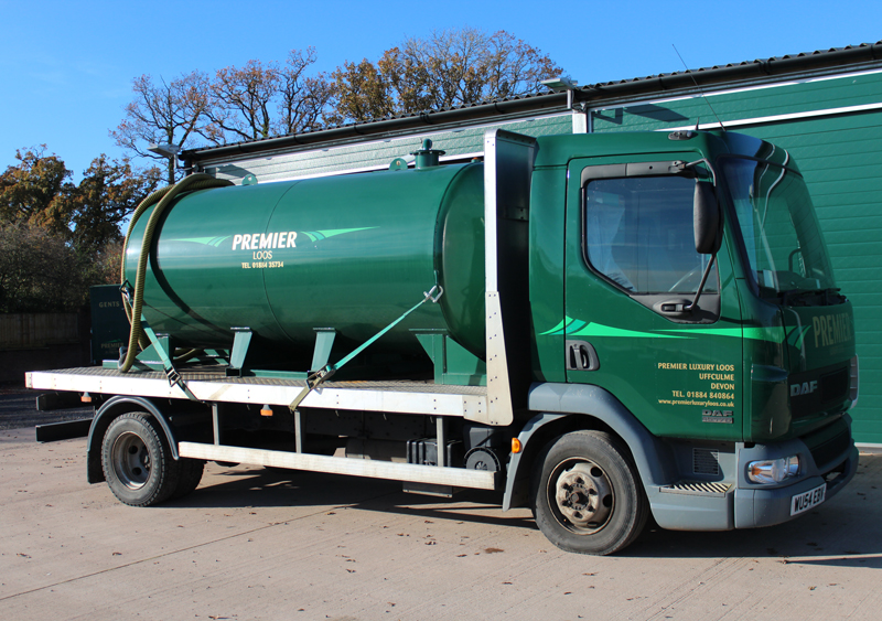 A green lorry with a tanker on the back. 